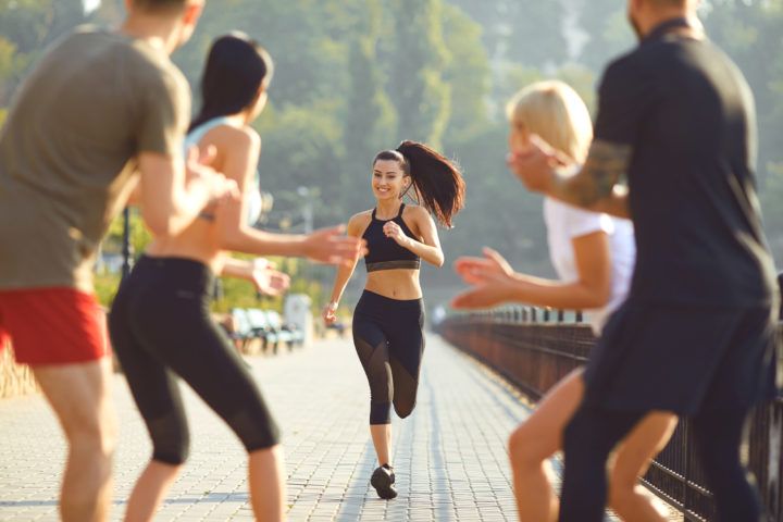 Grupa osób dopinguje biegnącą kobietę