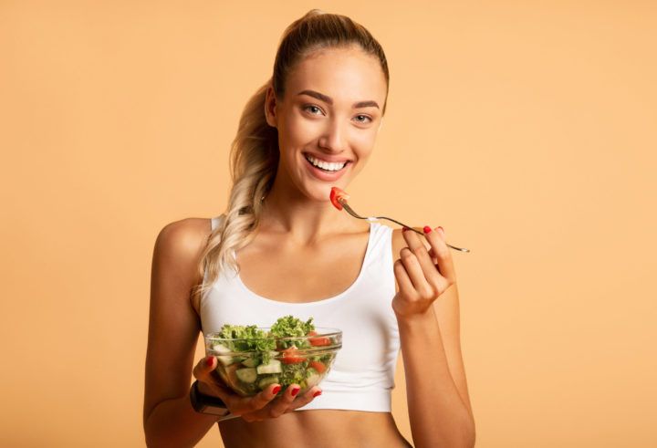 Kobieta w stroju fitness zjada sałatkę